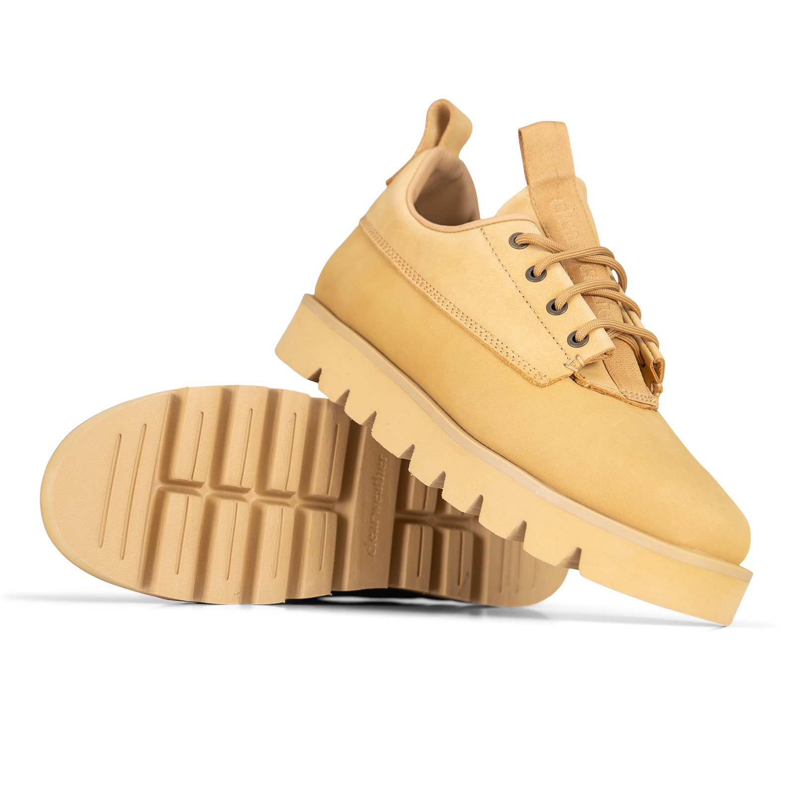 A pair of tan suede lace-up boots with chunky lug soles, shown on a clean white background with one boot standing upright and the other lying on its side to display the tread.