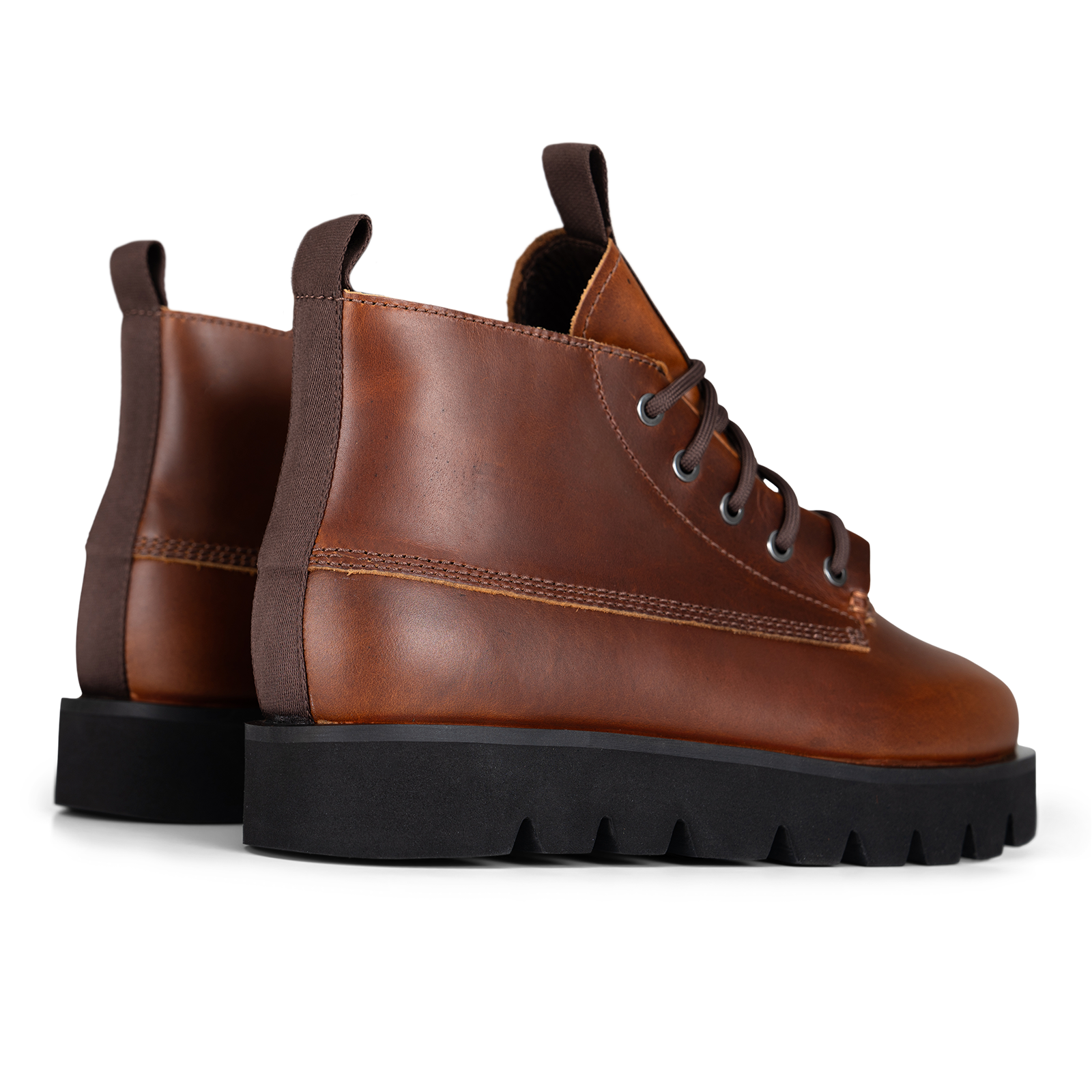 A pair of brown leather lace-up ankle boots with chunky black lug soles, shown on a clean white background.