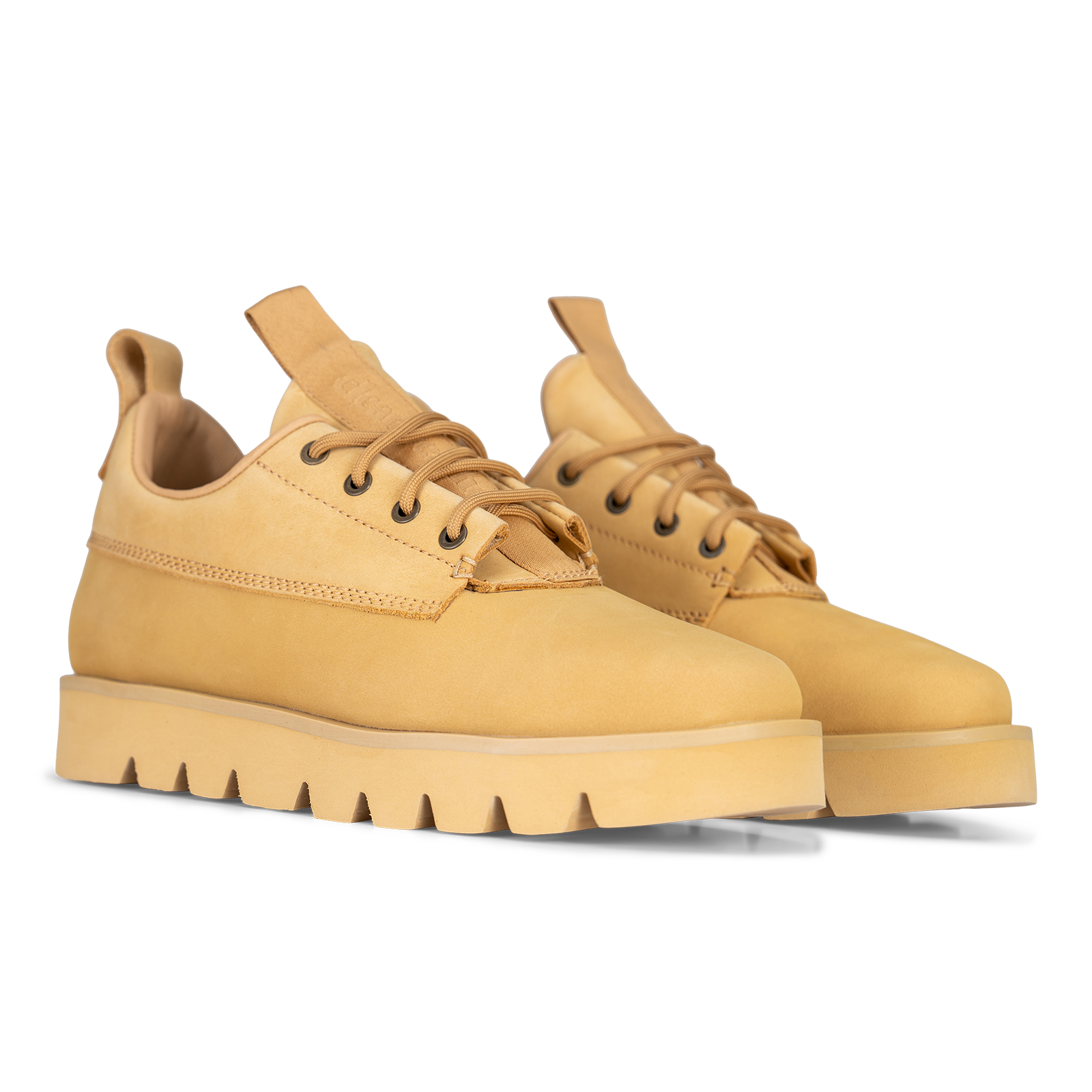 A pair of low-top lace-up boots in a warm tan suede-like material, featuring a chunky lug sole and pull tabs on the tongue, shown on a clean white background.