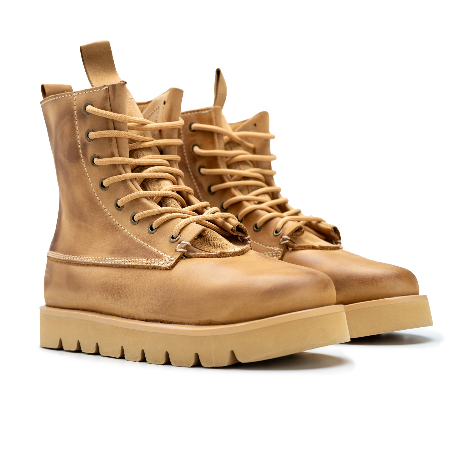 Pair of tan leather boots with thick soles on a white background