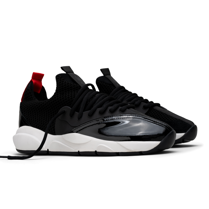 3/4 view, Cloudstryk Advantage is a runner with Black patent leather and suede overlays zoom mesh underlays, red heel pull molded lace holder, white eva midsol and a translucent black rubber outsole.